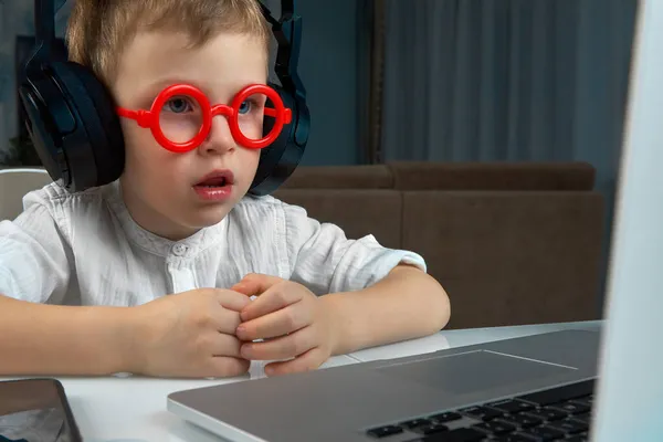 Ένα μικρό αγόρι με κόκκινα γυαλιά παίρνει ένα online εκπαιδευτικό μάθημα στο σπίτι — Φωτογραφία Αρχείου