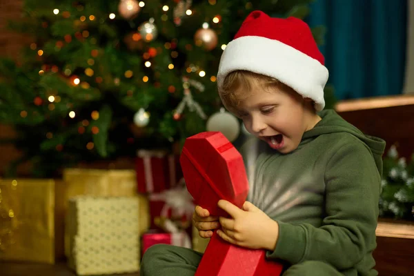 Niño Lindo Sombrero Navidad Abre Regalo Bajo Árbol Navidad Decorado — Foto de Stock