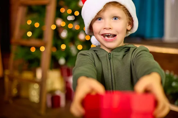 Niño Sombrero Navidad Está Sosteniendo Regalo Hermoso Paquete Sobre Fondo — Foto de Stock