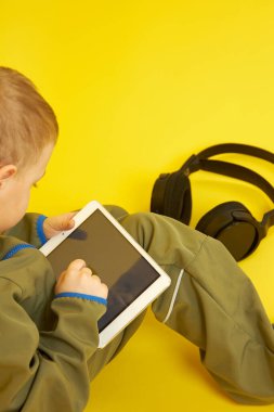 Kulaklıklı bir çocuk dijital tablet çalıyor.