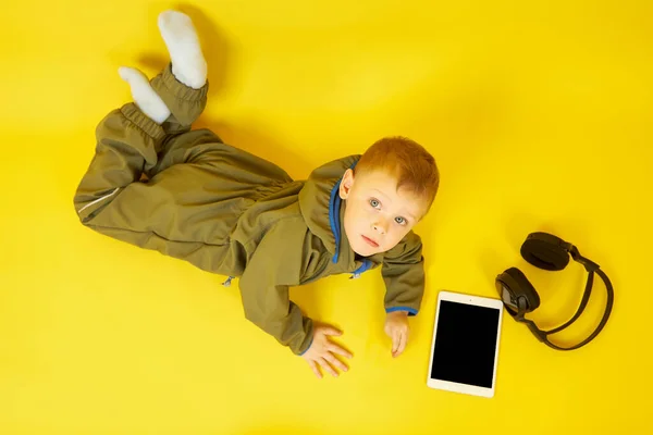 Ένα αγόρι με ακουστικά παίζει ένα ψηφιακό tablet — Φωτογραφία Αρχείου