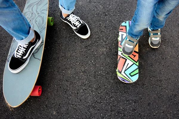 Un adolescent apprend à un enfant à faire du skateboard. — Photo