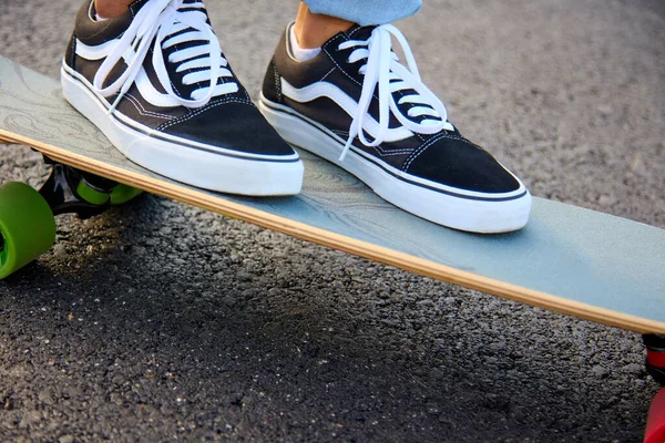 Adolescente monta un monopatín en la calle en zapatillas y jeans. — Foto de Stock