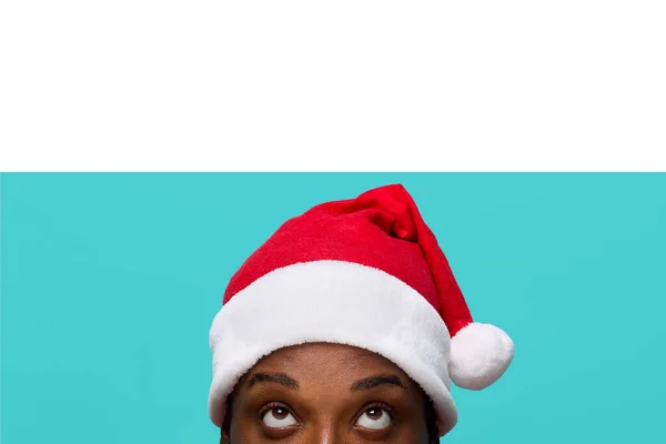 Afroamerykanin w czapce Świętego Mikołaja z wyrazistymi oczami patrzy uważnie w górę — Zdjęcie stockowe