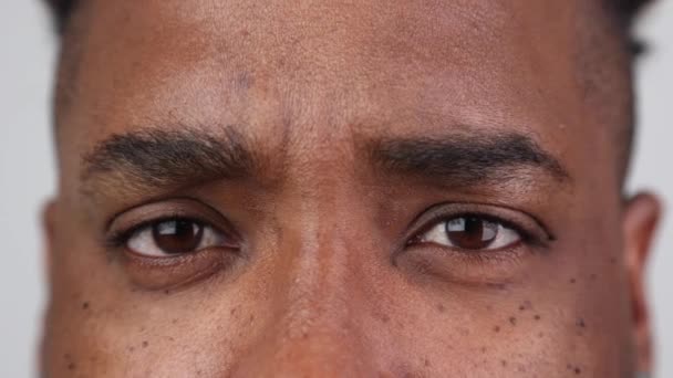 Vista de perto de um homem africano olhando para a câmera em um fundo branco — Vídeo de Stock
