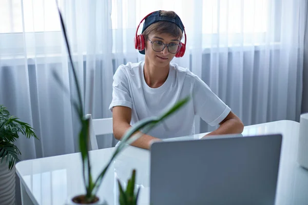 Σύγχρονη έφηβος φορώντας γυαλιά και ακουστικά επικοινωνεί με τους φίλους βίντεο. — Φωτογραφία Αρχείου