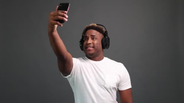 African-American man takes a selfie on a gray background. — Vídeo de Stock