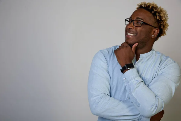 Hombre afroamericano con gafas mira hacia arriba con una sonrisa y una expresión reflexiva en su rostro — Foto de Stock