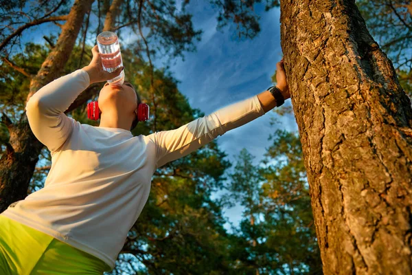 Exhausted runner-a woman feels bad because of dehydration or overtraining, drinks water