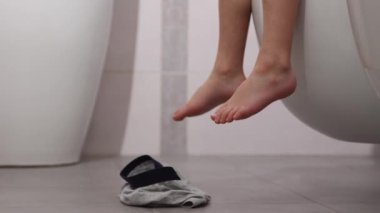 Asılı bir tuvalette oturan küçük bir çocuğun yakın çekimi.