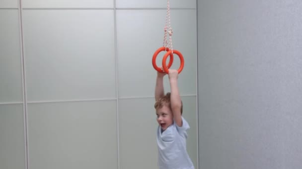 Pretty child is spinning at home on gymnastic rings — Wideo stockowe