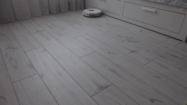 Современный робот пылесос пылесосит светлый пол в спальне. — стоковое видео