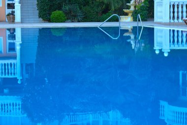 Large swimming pool with blue water and a staircase for descent in the hotel.