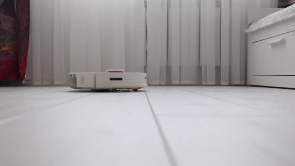 White robot vacuum cleaner effectively cleans the light laminate in the room — Vídeos de Stock