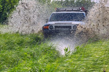 Off-road yarışında bir damla su. SUV tehlikeli bir su bariyerinin içinden geçiyor.