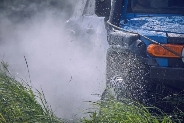 Tehlikeli bir su bariyerinin içinden geçen mavi bir off-road aracının yakın çekimi.. — Stok fotoğraf