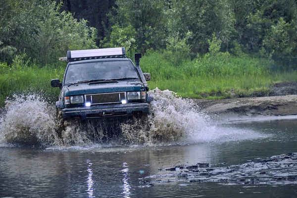 Samochód terenowy 4x4 przecina barierę wodną z rozpryskami przy dużych prędkościach. — Zdjęcie stockowe