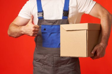 İş kıyafetleri içinde yükleyici karton bir kutuda bir paket getirdi..