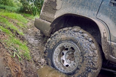 Çok kirli 4x4 off-road arabası yamaçtan kayarak büyük bir su birikintisine giriyor.