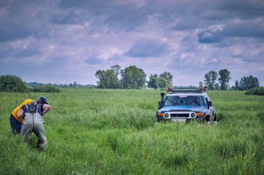 Atletlerden oluşan bir ekip 4x4 'lük bir off-road aracını çekmek için bir çapa hazırlıyor.