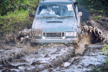 Mavi off-road aracı su çamurunda bir off-road yarışına katılıyor.