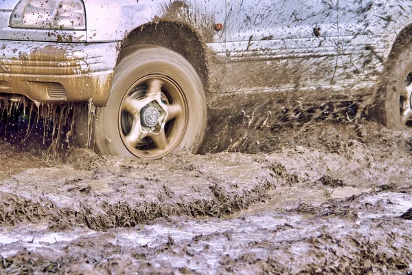 Wheels of the offroader are slipping in the mud and splashing slush on the car — Stock Photo, Image