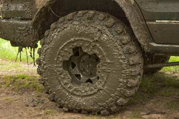 Dirty offroader wheel is standing on the road with the ground. — Stock Photo, Image