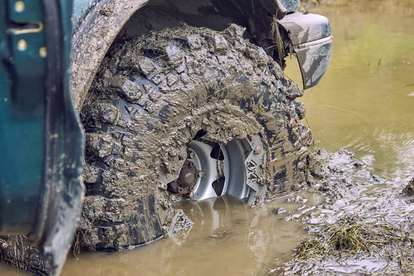 La rueda sucia de un coche todoterreno 4x4 está medio ahogada en un charco — Foto de Stock