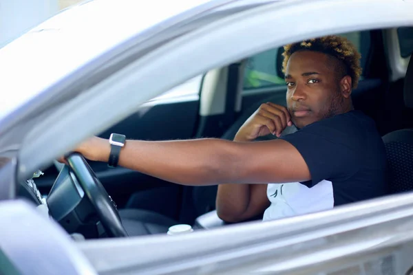 El hombre está sentado detrás del volante en el coche con la mano en el volante — Foto de Stock
