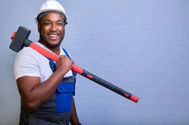 İş kıyafetleri ve şapkalı profesyonel müteahhit kameraya bakar ve gülümser.