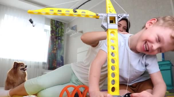 Мама катит игрушечную машину на своих сыновей назад, ребенок смеется от щекотки — стоковое видео
