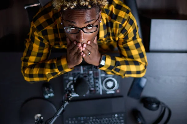 Vista superior de un joven africano sentado sosteniendo su cara en un estudio de grabación — Foto de Stock