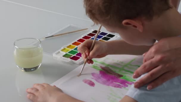 Close-up van kleine jongen tekening met verf en penseel samen met zijn moeder — Stockvideo