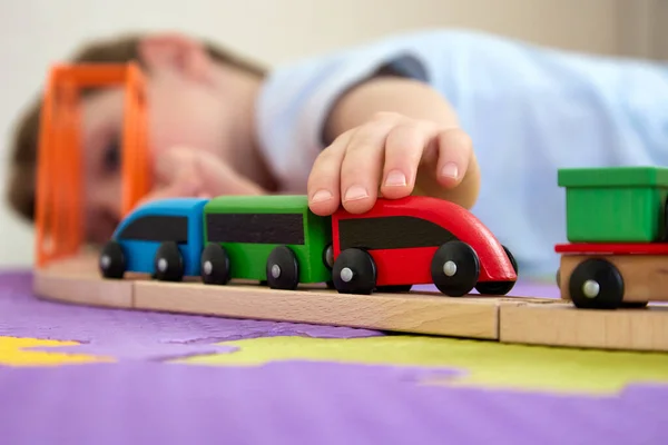 Close up smiling boy is having fun playing with wooden toys on puzzle mats — Stock Photo, Image