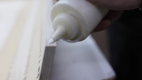 Carpenter applies carpenters glue to a piece of wooden furniture. — Stock Video