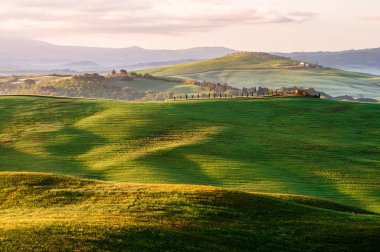 Bahar Tuscany. Güneş ışınlarıyla aydınlatılan yeşil tarlaların manzarası.