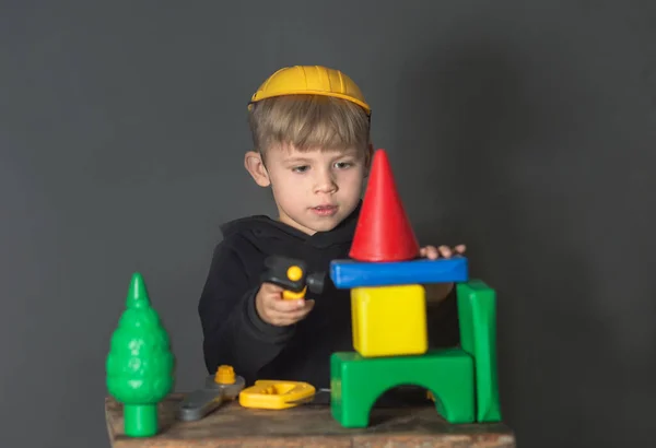 Ten Kluk Hraje Stavitele Staví Dům Kostek Hračkami Nosí Helmu — Stock fotografie