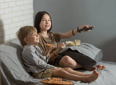 Bir erkek ve bir kız kanepede oturmuş televizyon izliyor, ev yapımı pizza ve patlamış mısır yiyorlar. Erkek ve kız kardeş iletişimi kavramı