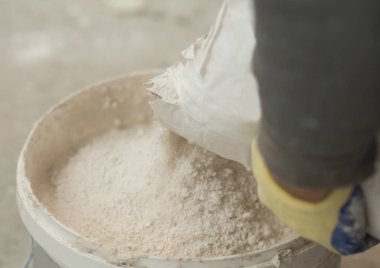 Kuru macunlu sıva solüsyonunu yakın plan bir kovadaki poşetten dökme işlemi..