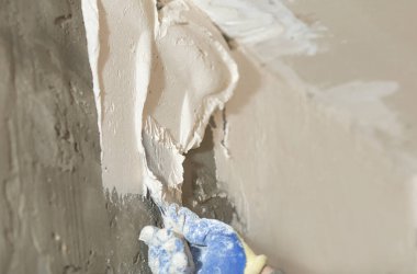 Duvara yakın plan bir spatula ile alçı havan macunu sürme işlemi