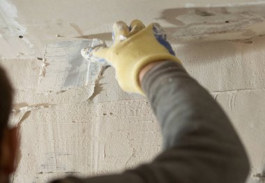 Duvara yakın bir spatulayla alçı havan macunu sürme işlemi.