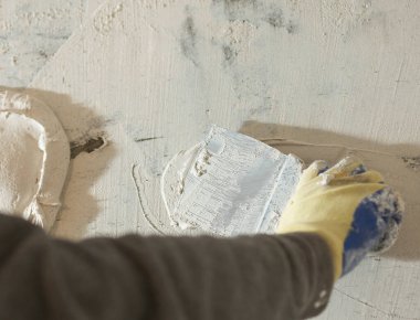 Duvara yakın bir spatulayla alçı havan macunu sürme işlemi.