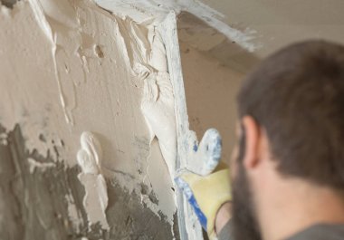 Duvara yakın bir spatulayla alçı havan macunu sürme işlemi.