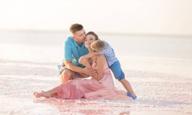 Bir kadın ve oğulları pembe bir gölün kıyısında oturuyorlar, sarılıyorlar ve sevişiyorlar.