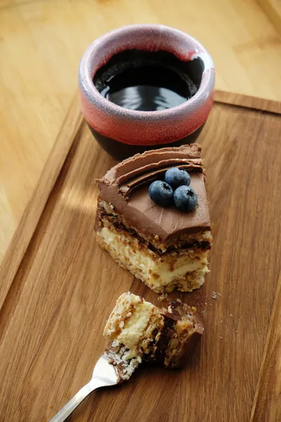 基辅的一块蛋糕 上面有巧克力糖霜 蓝莓和一杯咖啡 放在木板上 叉子上的一块蛋糕 — 图库照片