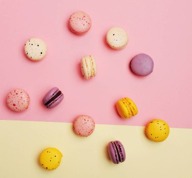 İki tonlu pembe ve bej renkli geometrik arka planda Fransız tatlı renkli badem kurabiyeleri.