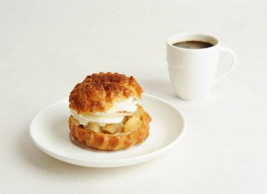 Beyaz tabakta kremalı Shu kek tatlısı ve bir fincan kahve. Beyaz arkaplan