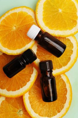 Citrus orange essential oil in dark glass bottles on fresh slices of orange. Cosmetic, healthy concept. Top view