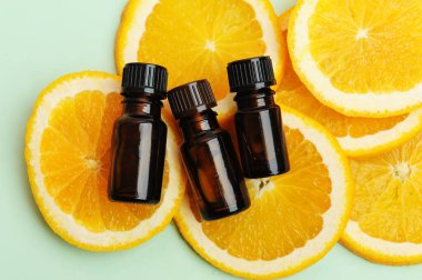 Essential oil in dark glass bottles on fresh slices of orange. Cosmetic, healthy concept. Top view