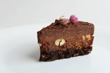 Slice of vegan chocolate nut cake on white blackground close-up